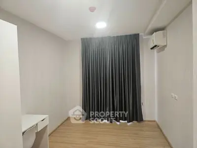Spacious empty room with wooden flooring and air conditioning