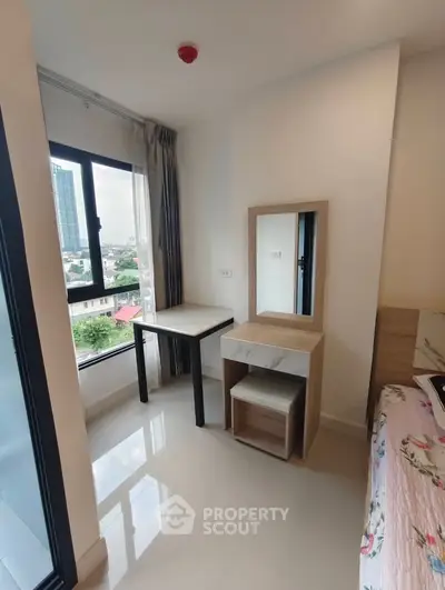 Bright bedroom with city view, featuring a modern desk and vanity set, perfect for urban living.