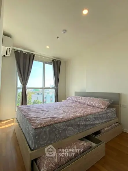 Bright and cozy bedroom with large window and wooden flooring, perfect for relaxation.