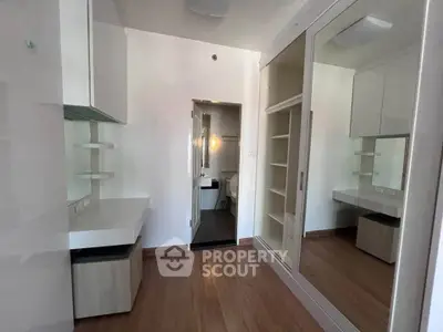Modern bedroom with mirrored wardrobe and wooden flooring, featuring a sleek desk and ample storage.