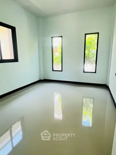 Bright empty room with glossy tiled floor and large windows, perfect for customization.