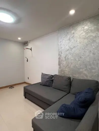 Modern living room with stylish gray sofa and textured accent wall, perfect for cozy relaxation.