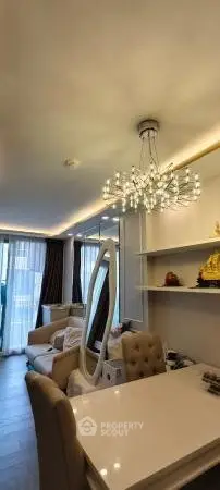 Elegant living room with modern chandelier and stylish furniture, featuring a cozy ambiance and natural light.