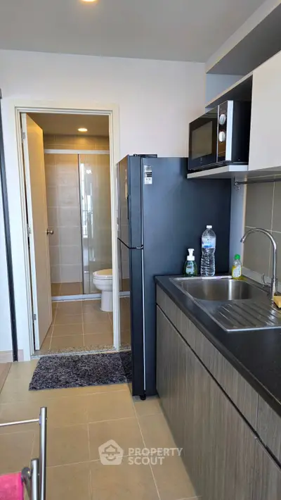 Modern kitchen with sleek appliances and view into a compact bathroom
