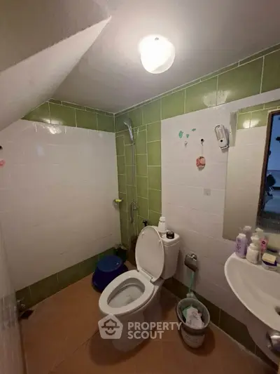 Cozy bathroom with green and white tiles, featuring a shower and modern fixtures.
