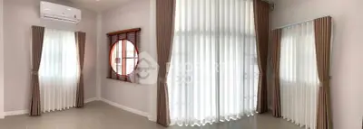 Spacious living room with large windows and elegant curtains, featuring a modern air conditioning unit.
