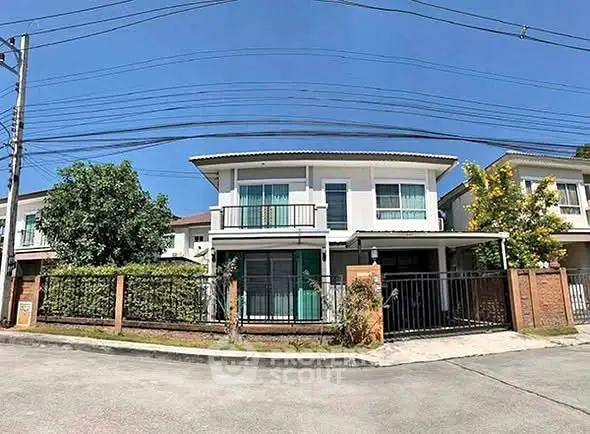 Charming two-story house with gated entrance and lush greenery in a serene neighborhood.