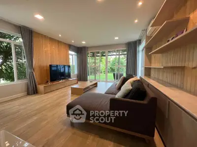 Spacious living room with modern decor and garden view, featuring a large sofa and entertainment center.