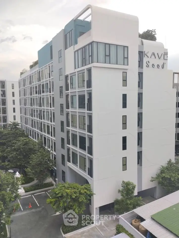 Modern multi-story apartment building with sleek design and large windows, surrounded by greenery.
