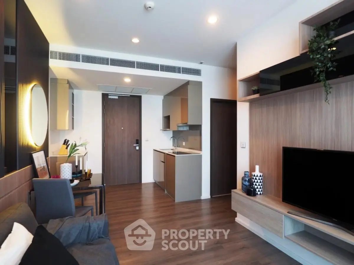 Modern living room with open kitchen, stylish decor, and wooden flooring in a contemporary apartment.