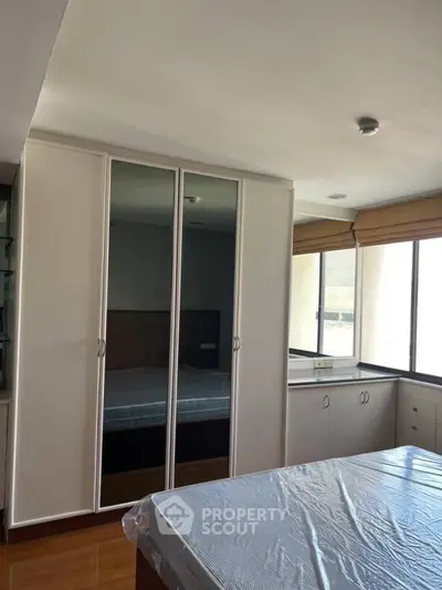 Spacious bedroom with large windows and mirrored wardrobe