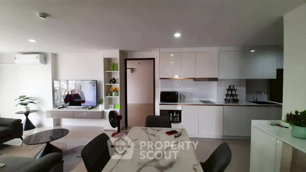 Modern open-plan living room with sleek kitchen and marble dining table