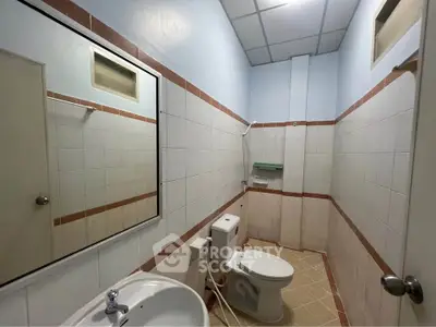 Compact bathroom with tiled walls, mirror, and modern fixtures in a real estate property.