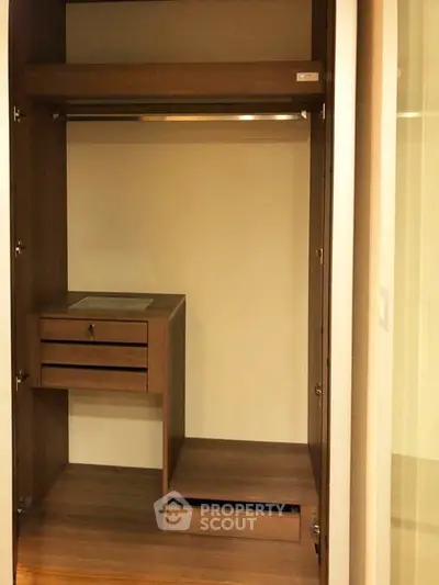 Spacious wooden walk-in closet with built-in drawers and hanging rod, perfect for organized storage.