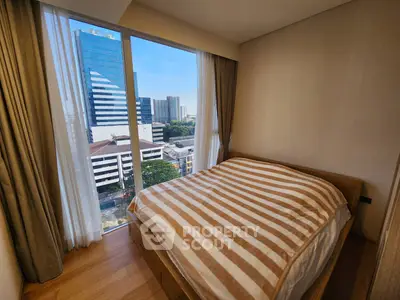 Cozy bedroom with city view and large window, featuring modern decor and natural light.