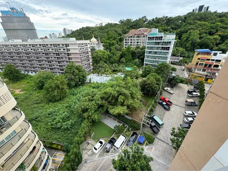 Scenic view of urban residential buildings surrounded by lush greenery and parked cars.