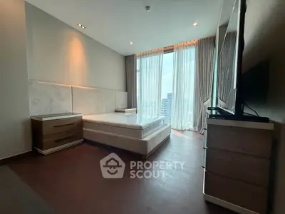 Spacious bedroom with large windows and modern furnishings in a high-rise apartment.