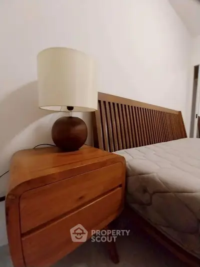 Cozy bedroom with wooden bed frame and matching nightstand, perfect for a serene retreat.