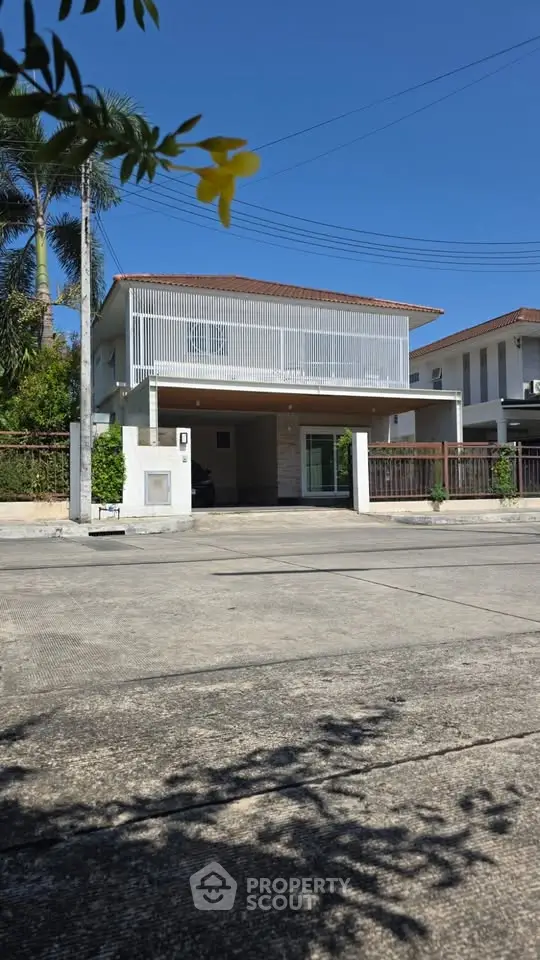 Modern two-story house with a spacious driveway and contemporary facade in a suburban neighborhood.