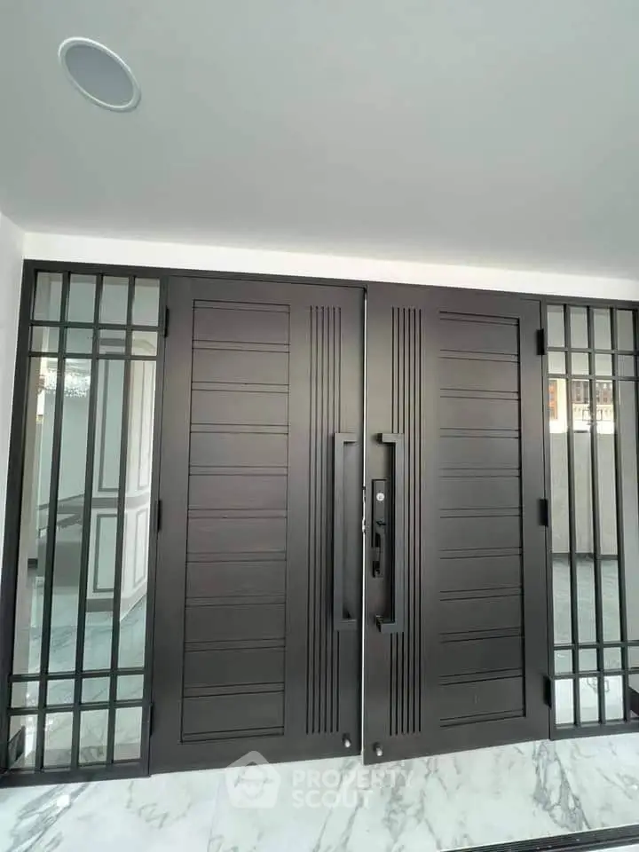 Elegant modern entrance with sleek double doors and marble flooring, showcasing luxury real estate design.