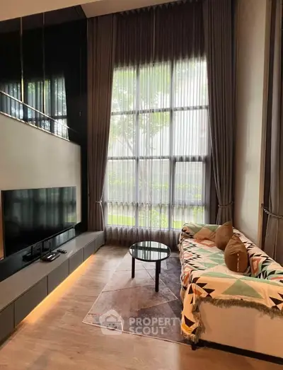Luxurious living room with high ceilings, large windows, and modern decor in a stylish apartment.