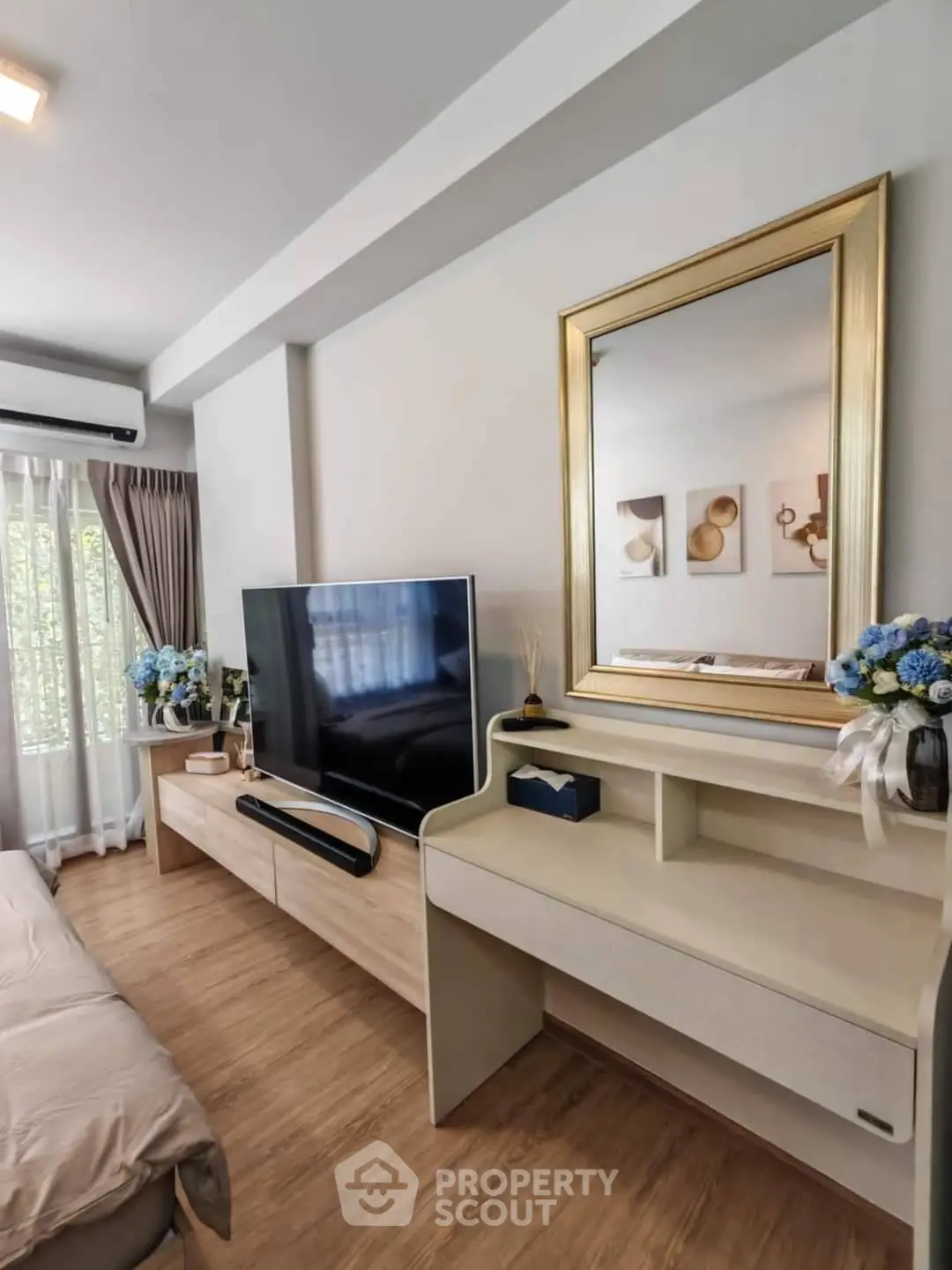Modern living room with stylish decor, large TV, and elegant mirror, perfect for relaxation and entertainment.
