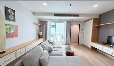 Spacious living room with modern decor and natural light, featuring a cozy sofa and balcony access.