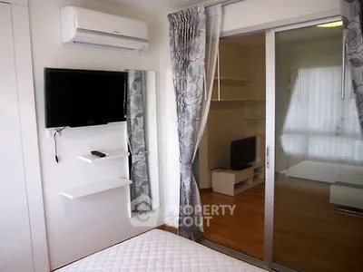 Modern bedroom with sliding glass doors and wall-mounted TV in a stylish apartment.