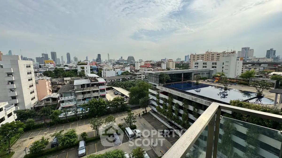 Stunning cityscape view from a high-rise balcony overlooking urban skyline and pool area.