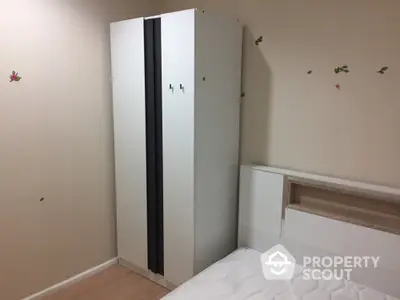 Cozy bedroom with modern wardrobe and comfortable bed, adorned with playful butterfly stickers, perfect for restful nights in a compact urban home.