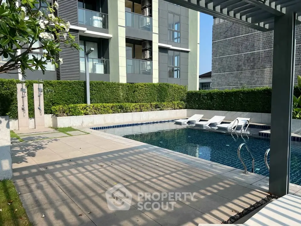 Luxurious condominium pool area with modern design and sun loungers.
