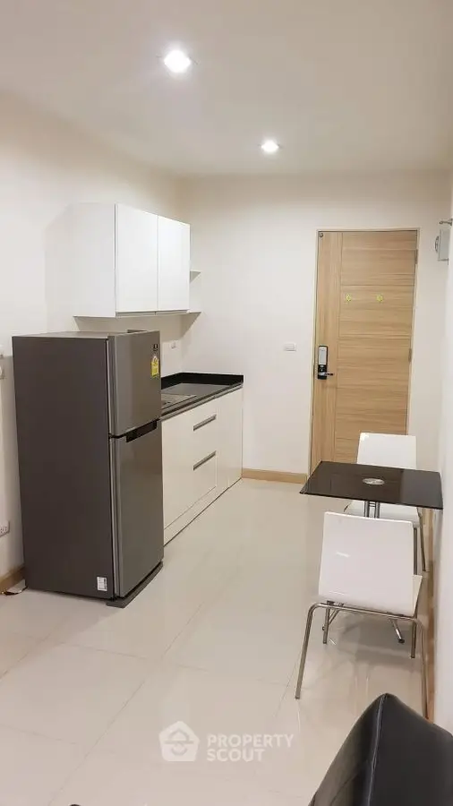 Modern kitchen with sleek appliances and dining area in a compact layout.