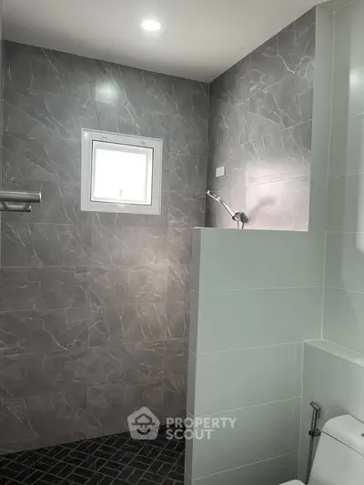 Modern bathroom with sleek gray tiles and a minimalist shower design.