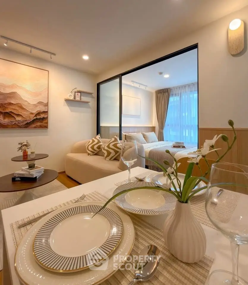 Modern open-plan living room with elegant dining setup and cozy bedroom view.