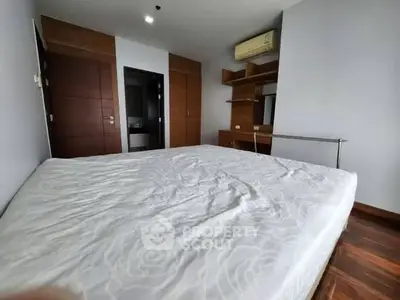 Spacious bedroom with wooden accents and built-in storage in modern apartment.