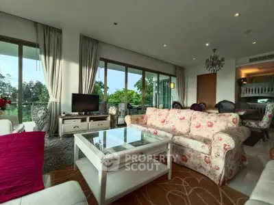 Spacious living room with elegant decor and large windows offering lush green views.