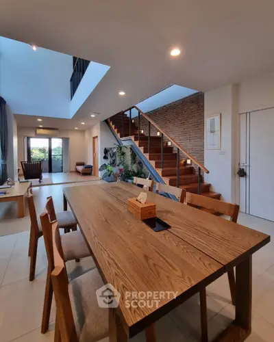 Spacious modern dining area with wooden table and staircase in elegant home.