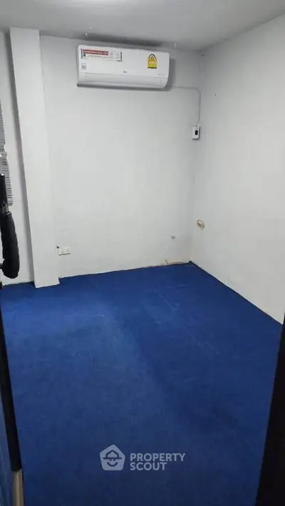 Compact room with blue carpet and wall-mounted air conditioner, ideal for small office or study.