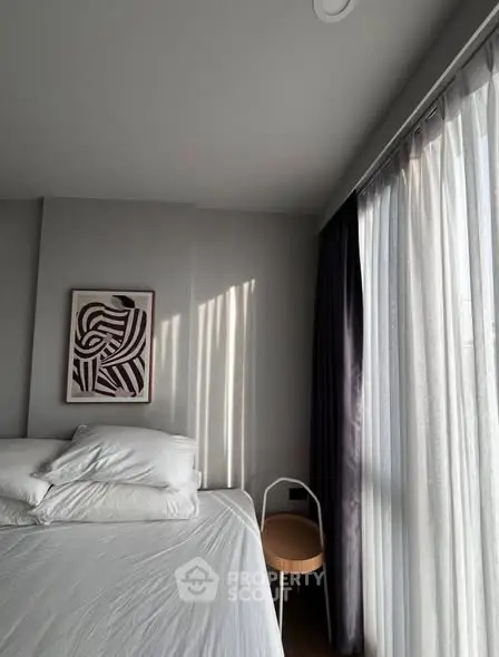 Modern bedroom with stylish decor and large window with sheer curtains.