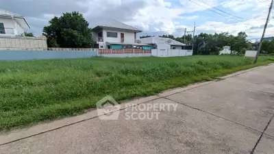 Spacious residential plot with lush greenery and neighboring houses, ideal for building your dream home.
