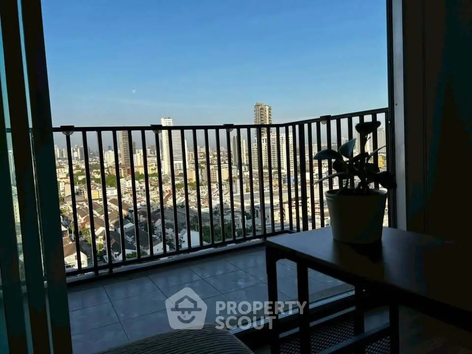 Stunning city view from a high-rise balcony with modern railing and cozy seating area.