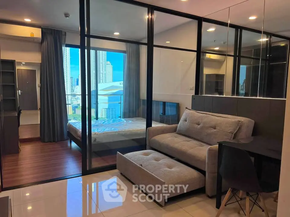 Modern condo interior with glass-walled bedroom and city view, featuring stylish furniture and sleek design.