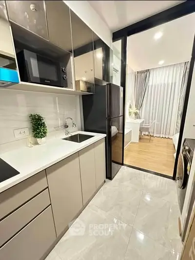 Modern kitchen with sleek cabinetry and open layout leading to a bright dining area.