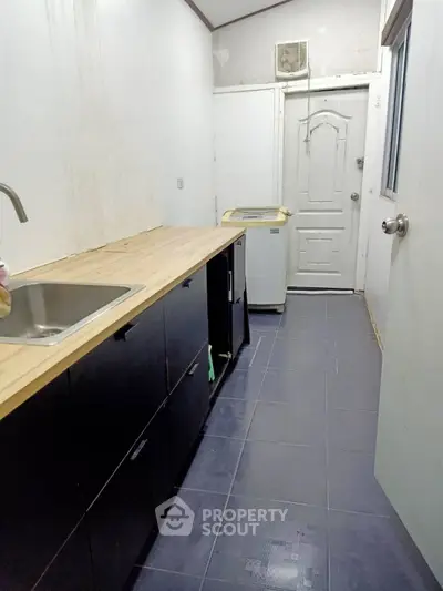 Compact kitchen with wooden countertop and black cabinets