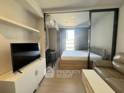 Modern studio apartment with cozy living area and bedroom, featuring sleek furniture and natural light.