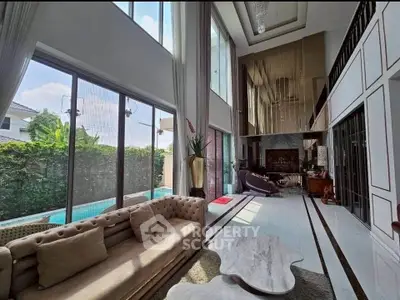 Luxurious living room with high ceilings and pool view, featuring elegant decor and ample natural light.