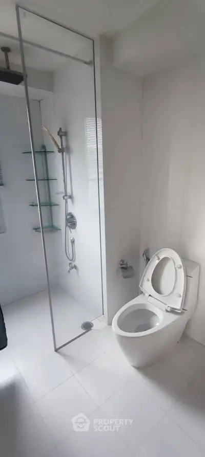 Modern bathroom with glass shower and sleek white fixtures in a contemporary home.
