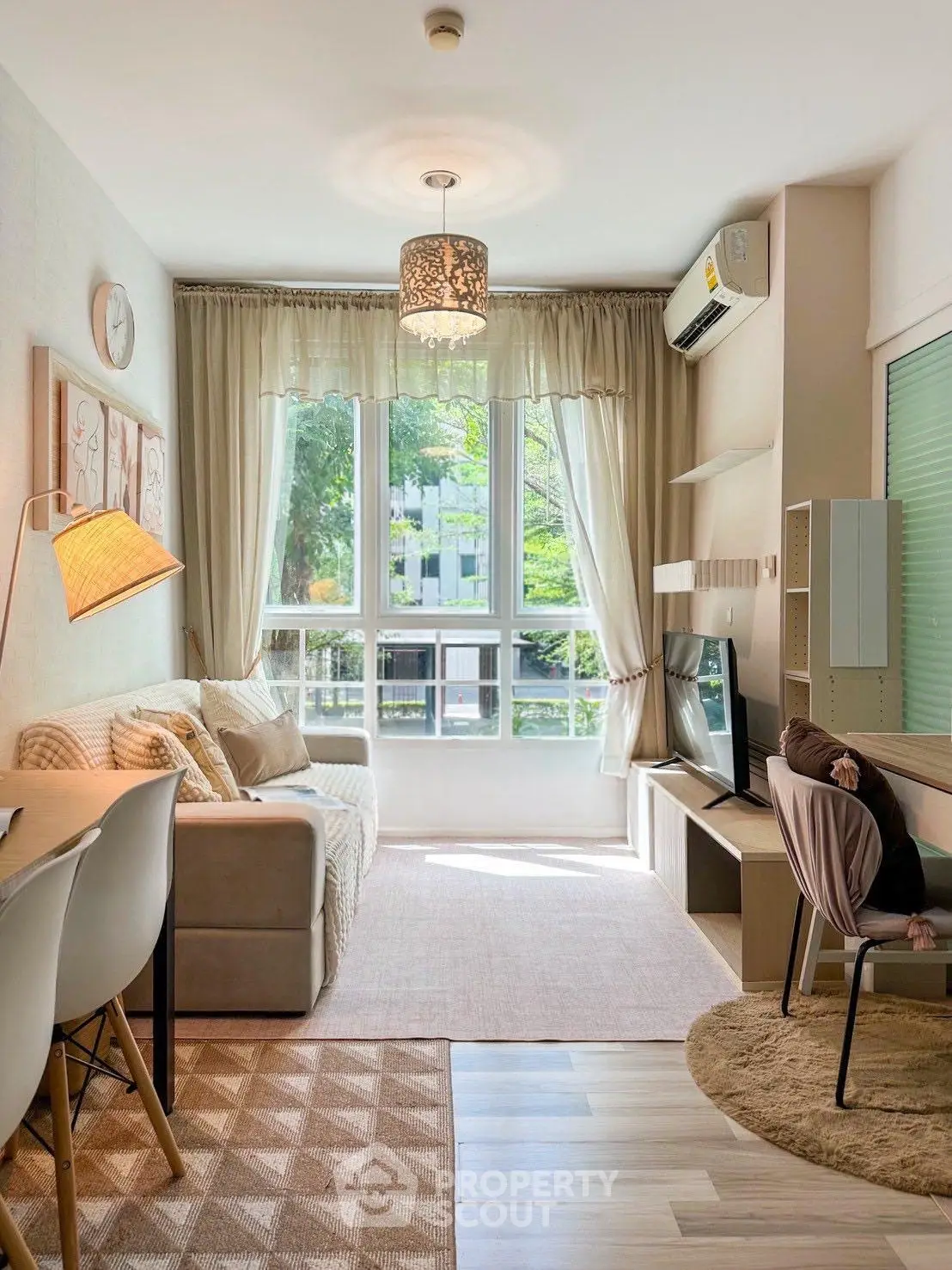 Charming living room with modern decor, large window, and cozy seating area, perfect for relaxation.