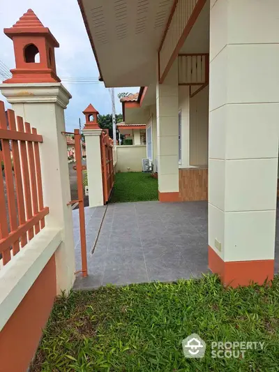 Charming exterior view of a modern house with tiled patio and lush green lawn.