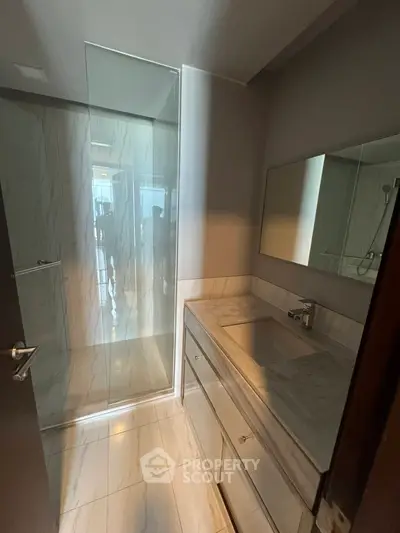 Modern bathroom with sleek marble finishes and glass shower enclosure